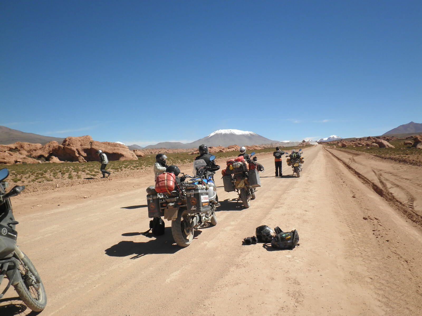 Adventure motorcycle riders with motorcycles loaded with gear stopping to look at the scenery on a dirt road on part of the Pan American trip