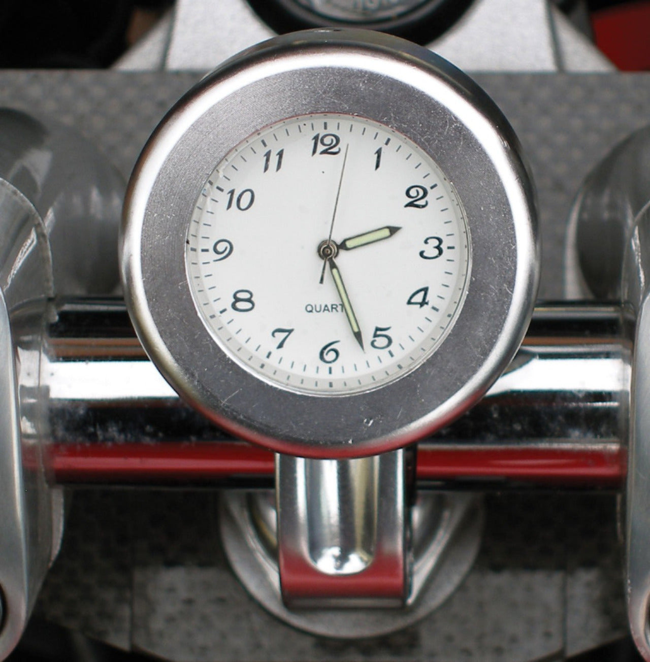 Silver analogue clock fitted to motorcycle handlebars